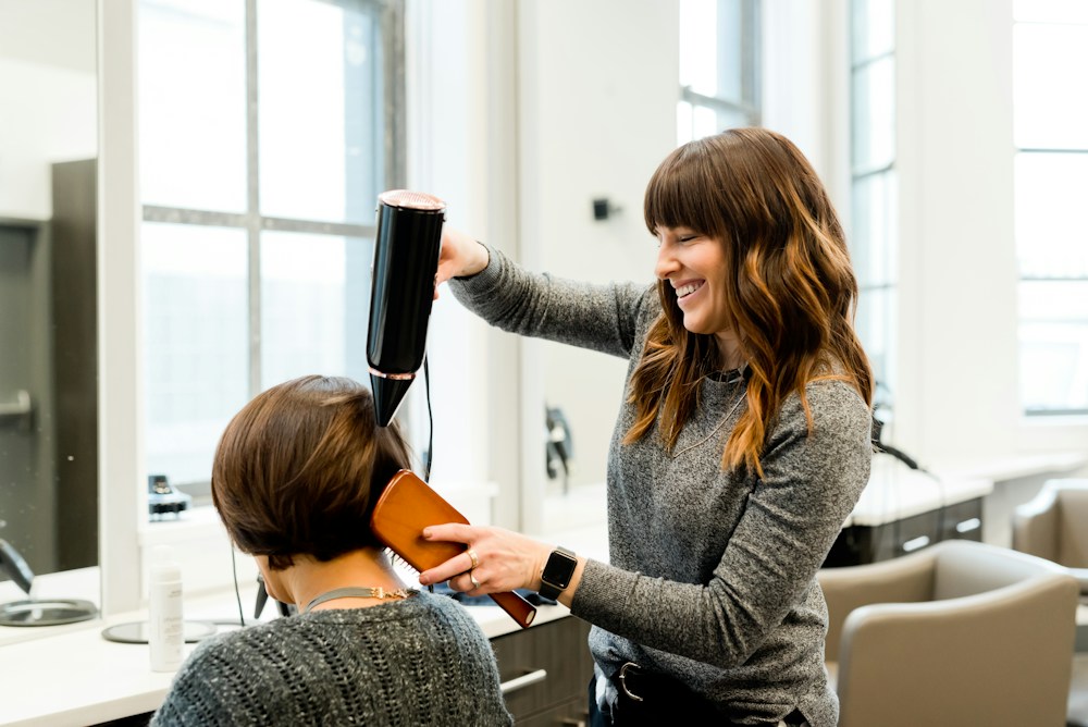 Coiffeuse réalisant un brushing dans un salon lumineux